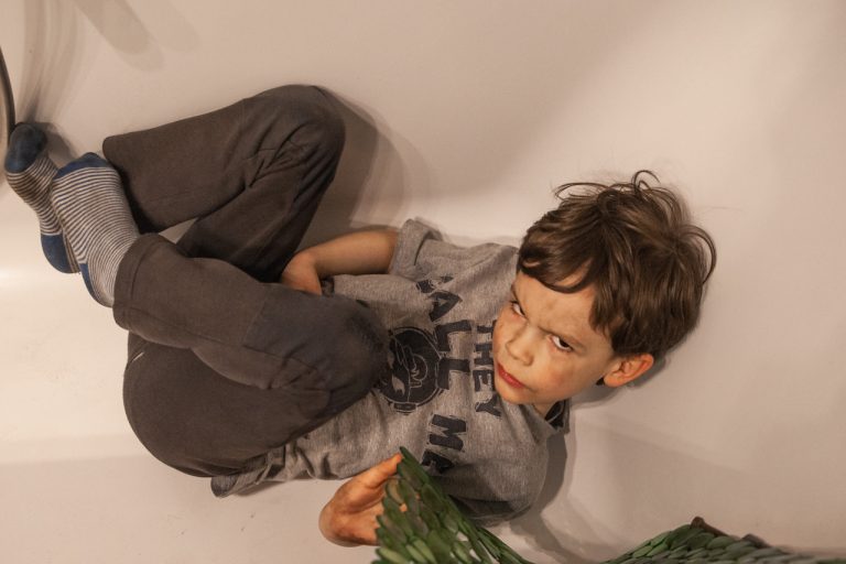 Ein kleiner Junge mit schmutzigen Geschit und Kleidung in der Badewanne