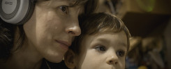 Eine Frau mit Kopfhörer umarmt das Kind beim Anschauen von einem Theater